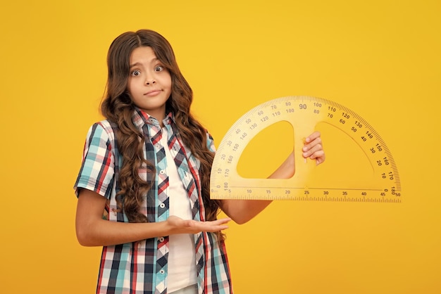 Back to school school girl hold ruler measuring isolated on yellow background shocked surprised teenager girl