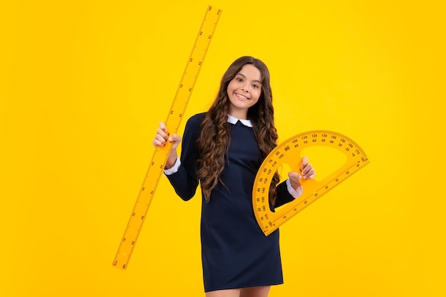 Back to school School girl hold ruler measuring isolated on yellow background