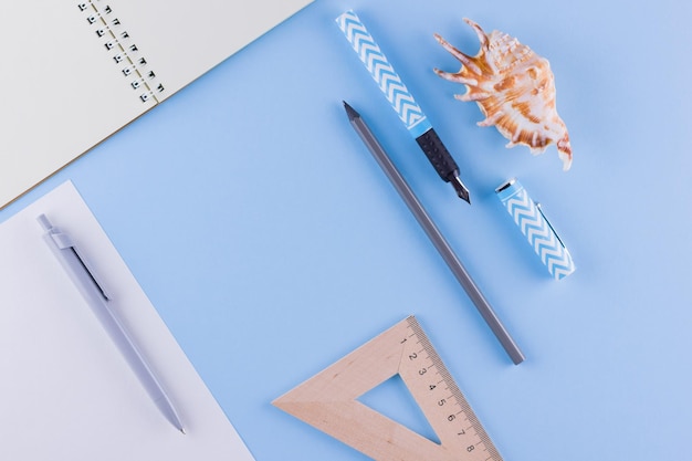 Photo back to school school stationery and seashell on blue background pens pencil and gon