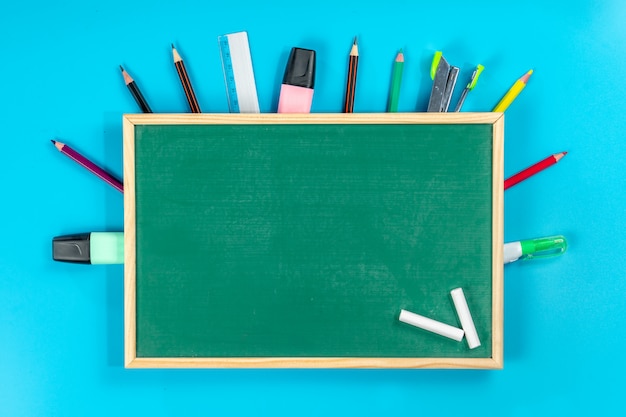 Back to school . school supplies and green blackboard on blue 