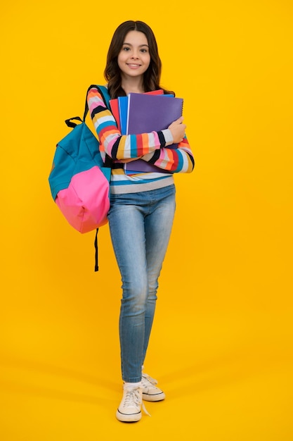 Back to school Schoolgirl student hold book on yellow isolated studio background School and education concept Teenager girl in school uniform Happy teenager positive and smiling schoolgirl