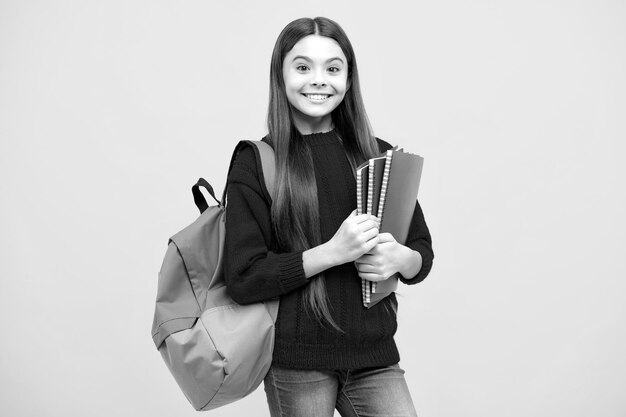 Back to school Schoolgirl student hold book on yellow isolated studio background School and education concept Teenager girl in school uniform