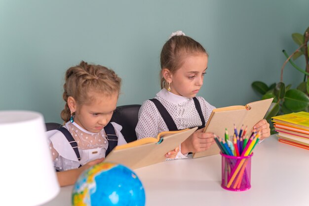 Back to school schoolgirls write draw in a notebook sitting at the table and do homework