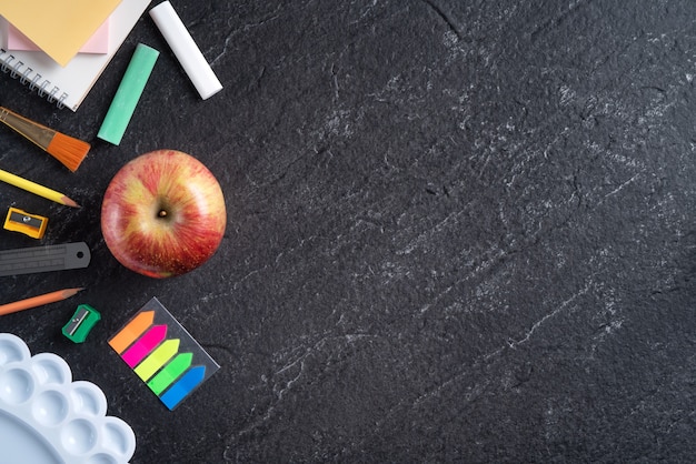 Back to school student design concept, top view of stationery over slate black table background with copy space.