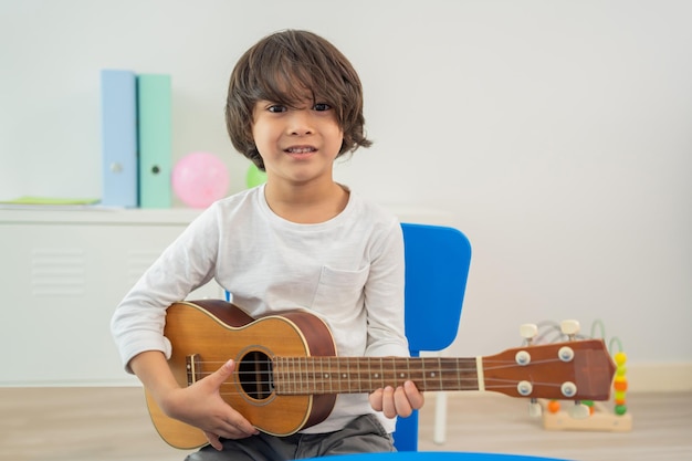 Back to school and summer course. little children play guitar\
in kindergarten classroom.