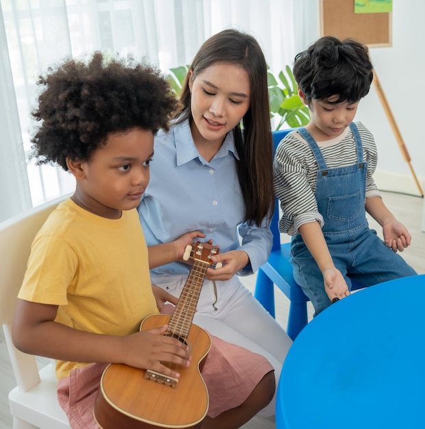 Back to school and summer course. little children play guitar\
in kindergarten classroom.