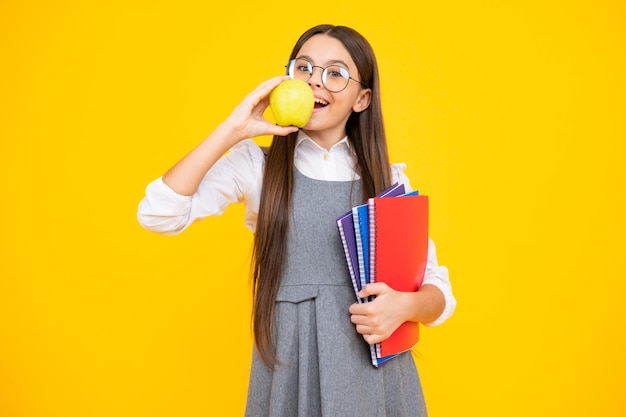 Back to school Teenage school girl with bag hold apple and book ready to learn School child on isolated yellow studio background