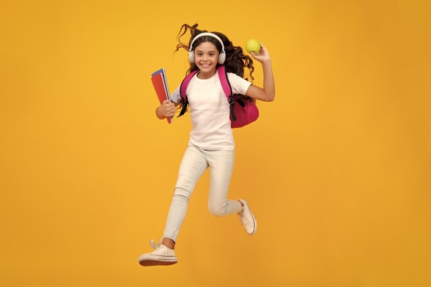 Back to school teenager school girl with backpack and headphones hold books ready to learn school