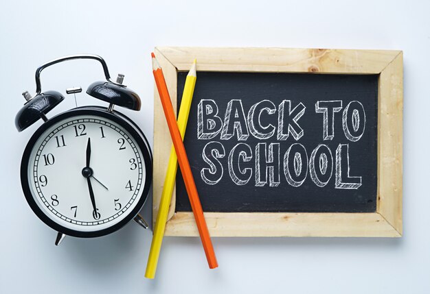 Photo back to school text. alarm clock, color pencil and blackboard on white background