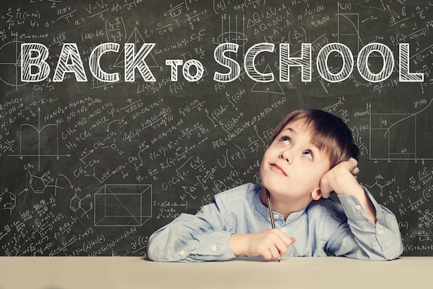 Back to school text and happy kid on chalkboard background