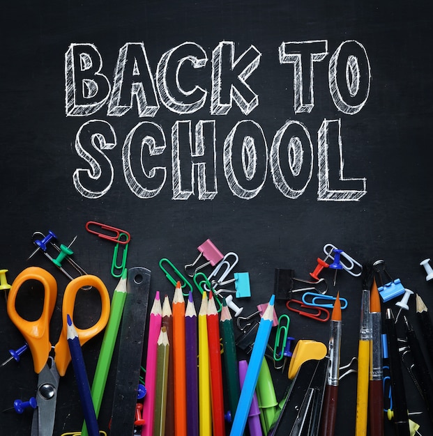 Photo back to school text. school stationary on blackboard top view