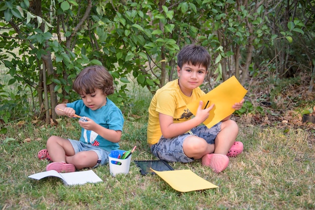 学校に戻る公園で手にノートと絵の具を持った2人の幸せで陽気な子供たち