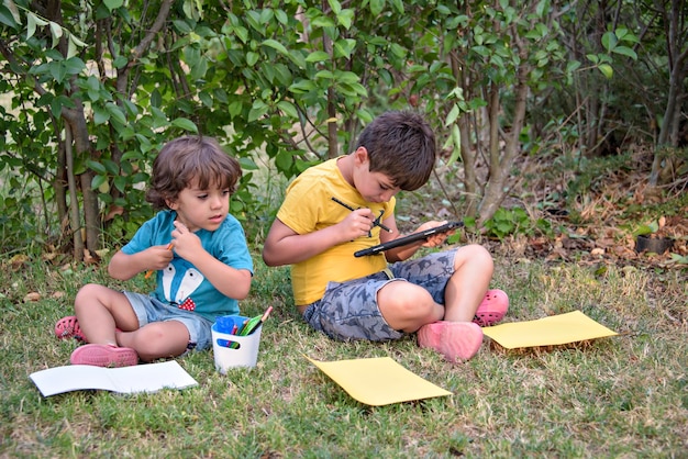 学校に戻る公園で手にノートと絵の具を持った2人の幸せで陽気な子供たち