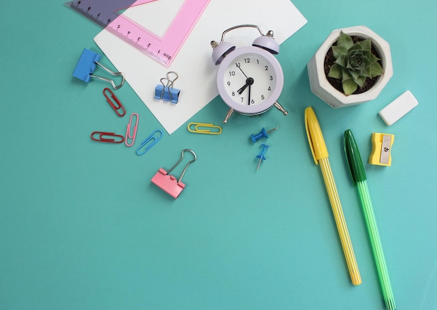 Back to school with stationary notebook and alarm clock on white student desk background top view mock up