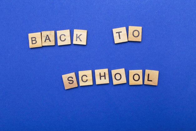 Back to school word made by wooden cubes on a blue background