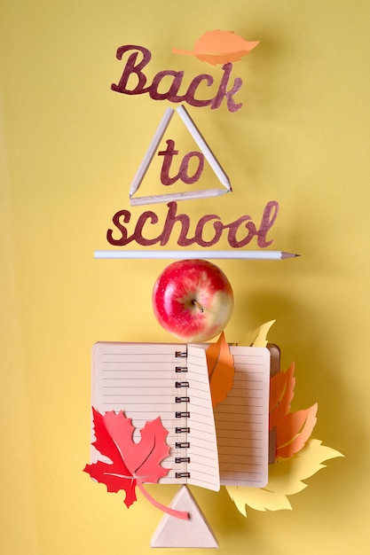 "Back to schooll" cut-out text among balancing stationary objects and apple