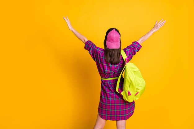 Back side photo of young lady raising hands wear mini pink dress bag hat isolated on yellow color background