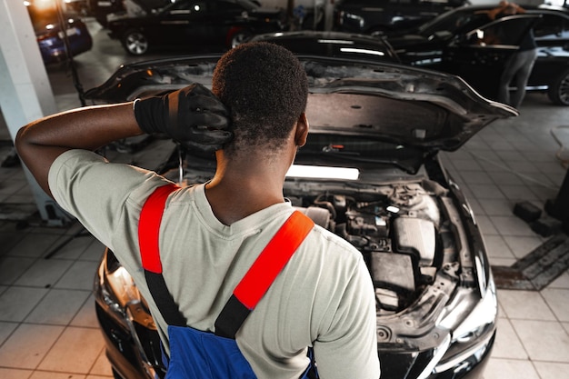 Back view of an african male mechanic repairing car in garage