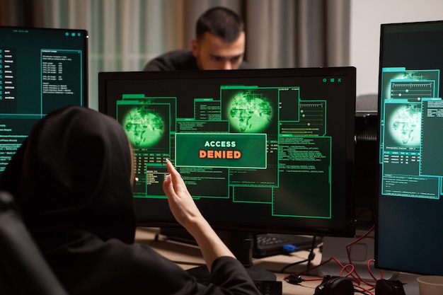 アクセスが拒否された後の怒っている女性ハッカーの背面図がコンピューターのデスクトップに表示されます。
