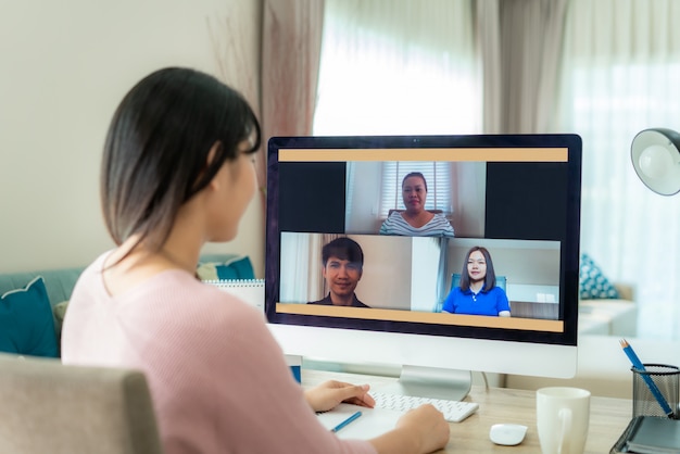 Back view of Asian business woman talking to her colleagues about plan in video conference.