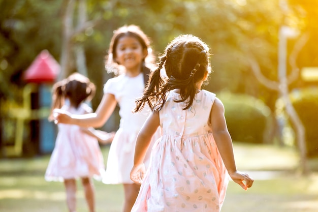 Back view of asian child girl running to her friend and play together in the park in vintage color tone