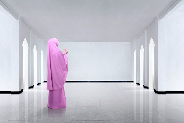 Back view of asian muslim woman raising hand and praying