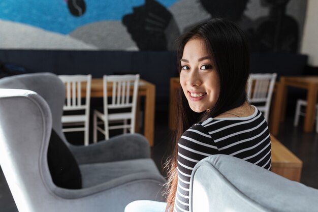 Back view of Asian woman sitting in cafeteria