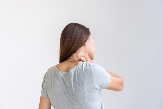 白い背景で隔離の首の痛みに苦しんでいるアジアの女性の背面図。コピースペース