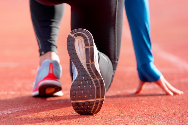 Vista posteriore di un atleta si prepara per la gara su una pista da corsa. focus sulla scarpa di un atleta che sta per iniziare una gara nello stadio.