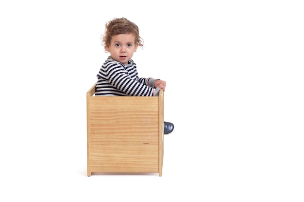 Back view of a baby boy sitting on chair turned and looking at camera on white background