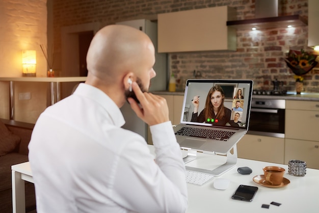 A back view of a bald guy who is working remotely on laptop at home.