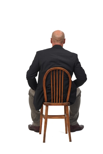 Back view of a bald man sitting on chair on white background