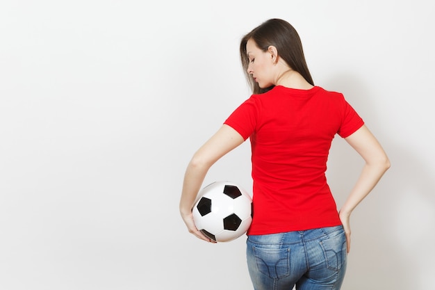 Back view beautiful european young sexy woman, football fan or\
player in red uniform holding classic soccer ball isolated on white\
background. sport, play football, health, healthy lifestyle\
concept.