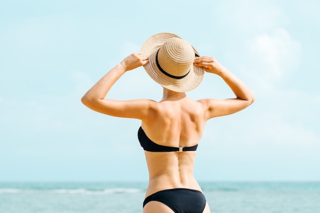 Back view of a beautiful woman posing in black swimwear bikini