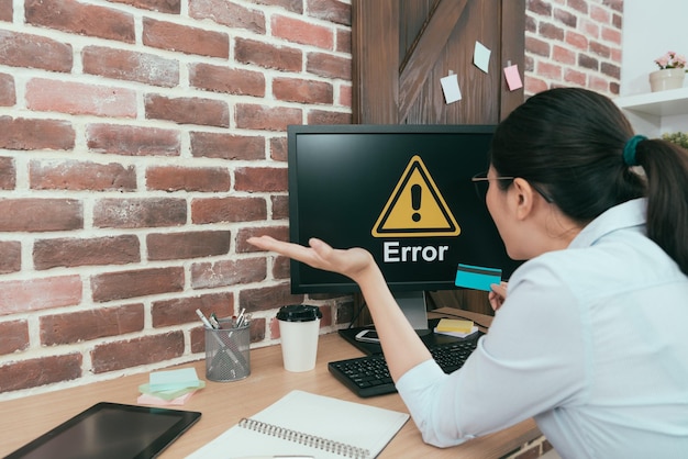 back view of beauty suit lady sitting on office working desk using credit card e-commerce system paying online shopping getting error warning feeling unhappy.