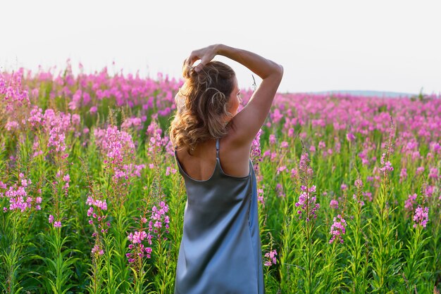 Fireweed牧草地に金髪の女性の背面図