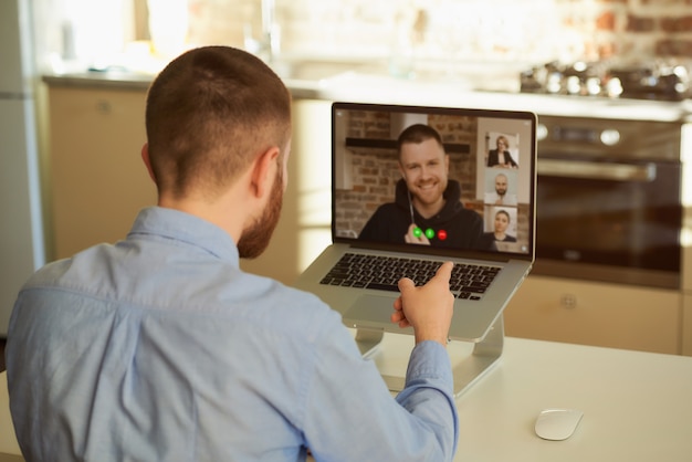 Vista posteriore di un capo che ascolta il suo dipendente in una riunione video su un computer portatile