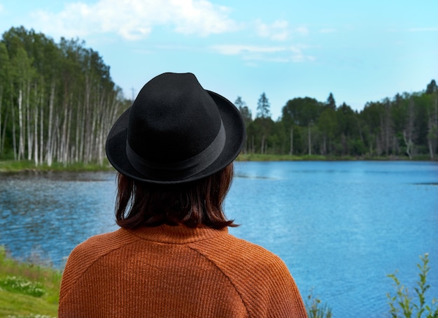 Back view of brunette lady looking at lake in Karelia