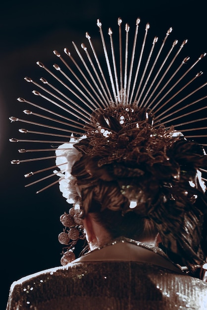 Back view of brunette woman with unusual creative headdress with metallic lines and vintage outfit. Old-fashioned style