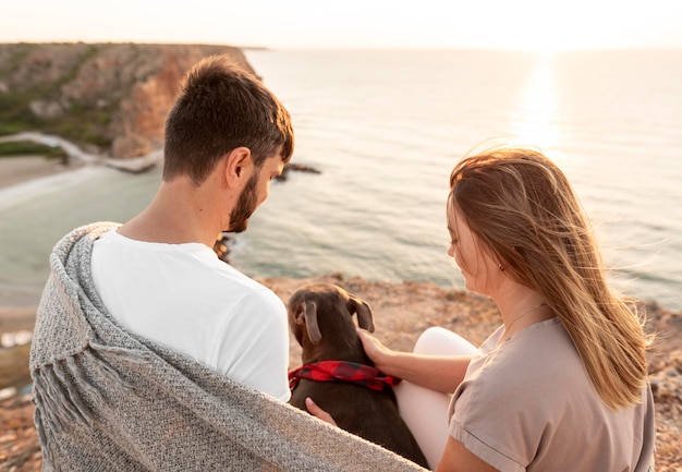 Photo back view couple enjoying the sunset with their dog