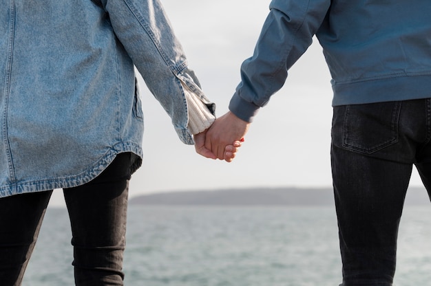 Photo back view couple holding hands at seaside