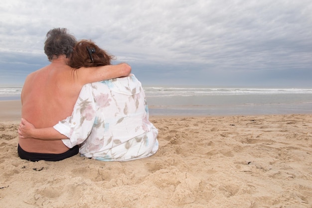 Back view of a couple sit on beach