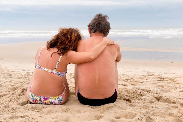 Back view of a couple sit on beach