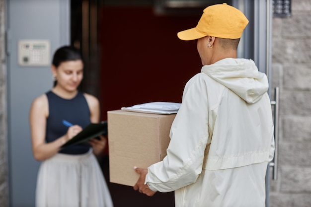 Back view of delivery person holding box while waiting for client signing documents copy space