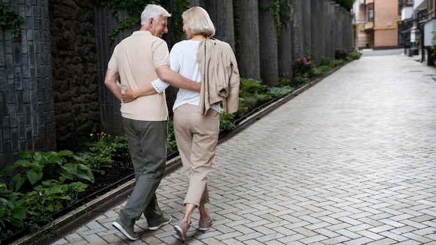 Photo back view of embraced senior couple taking a walk outdoors