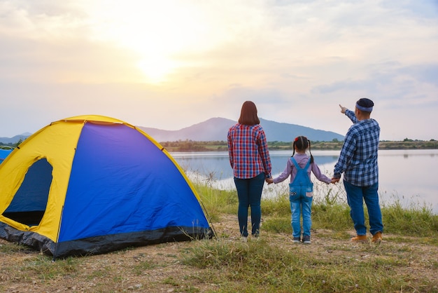 Photo back view of family watching sunset in the evening at camping site by the lake