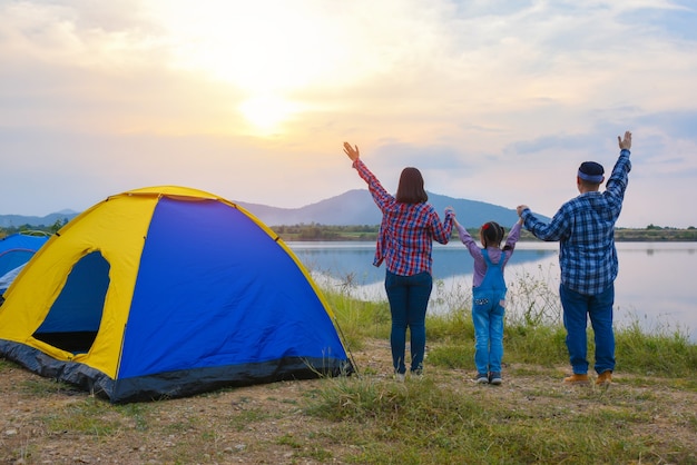 湖のほとりのキャンプ場で夕方に夕日を見ている家族の背面図