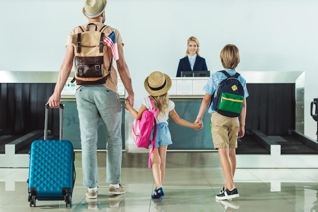 back view of family with backpacks going to check in desk at airport