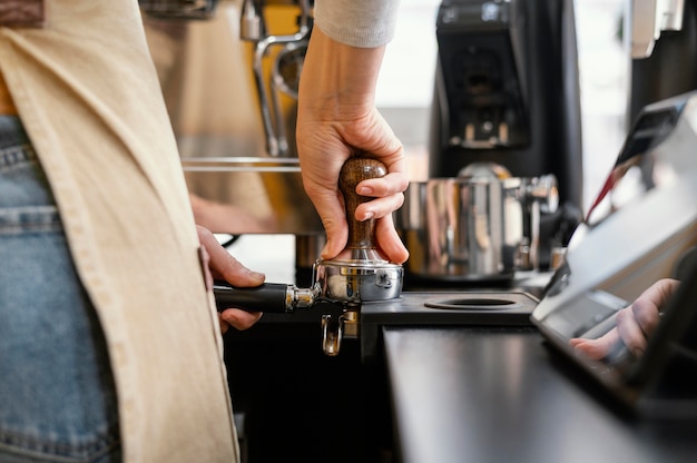 Vista posteriore del barista femminile utilizzando la macchina del caffè