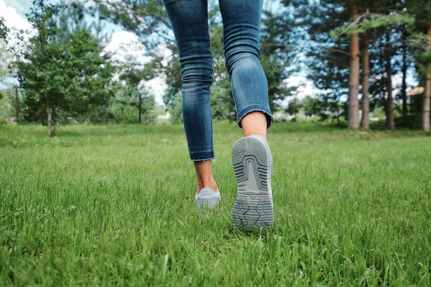 Back view of female legs walking on grass